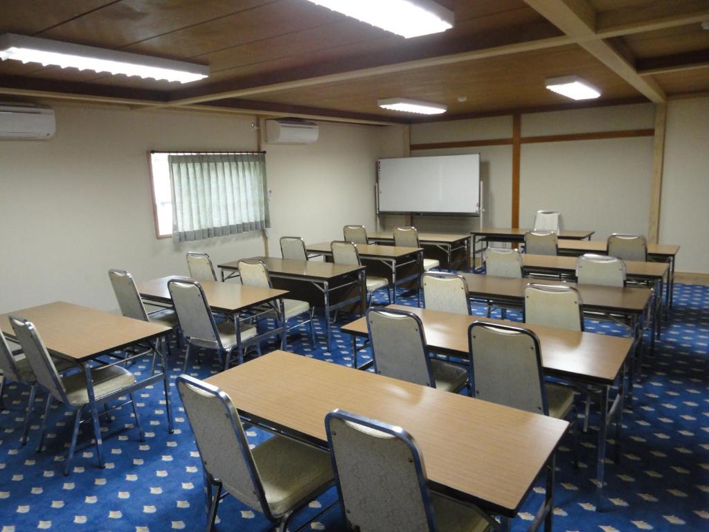 une salle de classe vide avec des tables et des chaises et un tableau blanc dans l'établissement Lake Side Hotel Minatoya, à Inawashiro