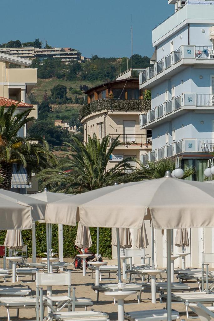 une rangée de chaises et de parasols devant un bâtiment dans l'établissement Residence Palazzo Gasparroni, à Tortoreto Lido