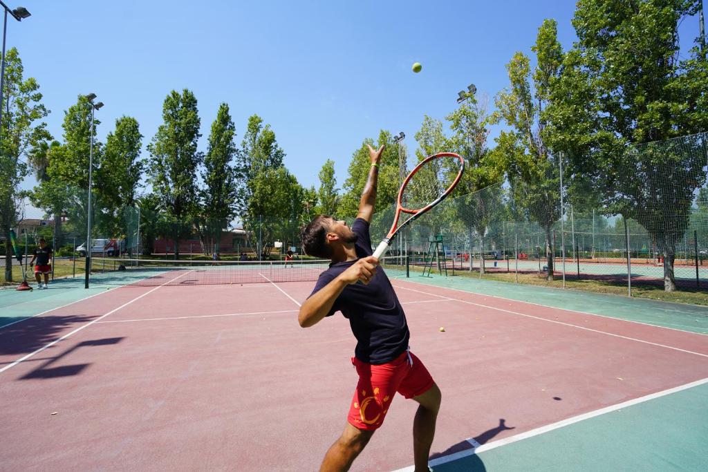 un homme servant une balle de tennis sur un court de tennis dans l'établissement Futura Club Itaca Nausicaa, à Rossano