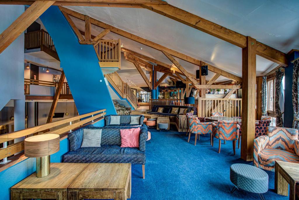 un salon avec moquette bleue et poutres en bois dans l'établissement Hôtel Le Montana, à La Tania