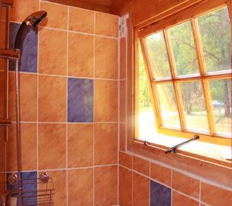 La salle de bains est pourvue d'une douche et d'une fenêtre. dans l'établissement Les yourtes de Bascot, à Vaylats