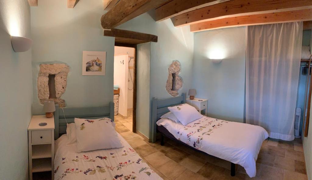 deux lits dans une chambre aux murs bleus dans l'établissement Gîte Le Pressoir, à Cahuzac-sur-Vère