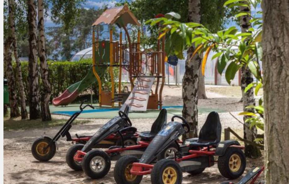 3 scooters pour personnes à mobilité réduite garés devant une aire de jeux dans l'établissement Mobilhome familial de luxe 3 chambres, à Onzain