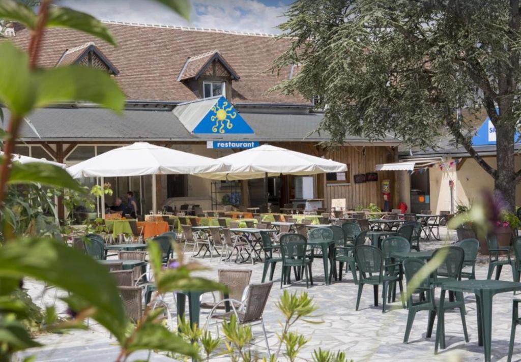 un patio extérieur avec tables, chaises et parasols dans l'établissement Mobilhome familial de luxe 3 chambres, à Onzain