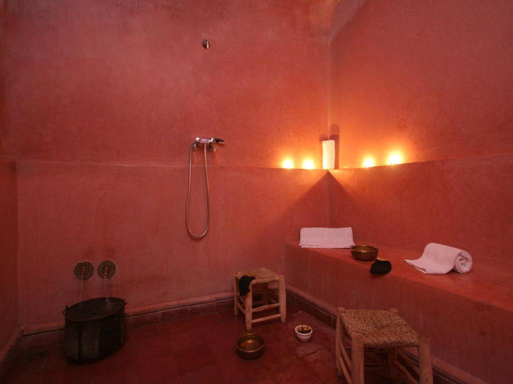 La salle de bains est pourvue d'une douche dans un mur rouge. dans l'établissement Riad Sidi Ayoub, à Marrakech