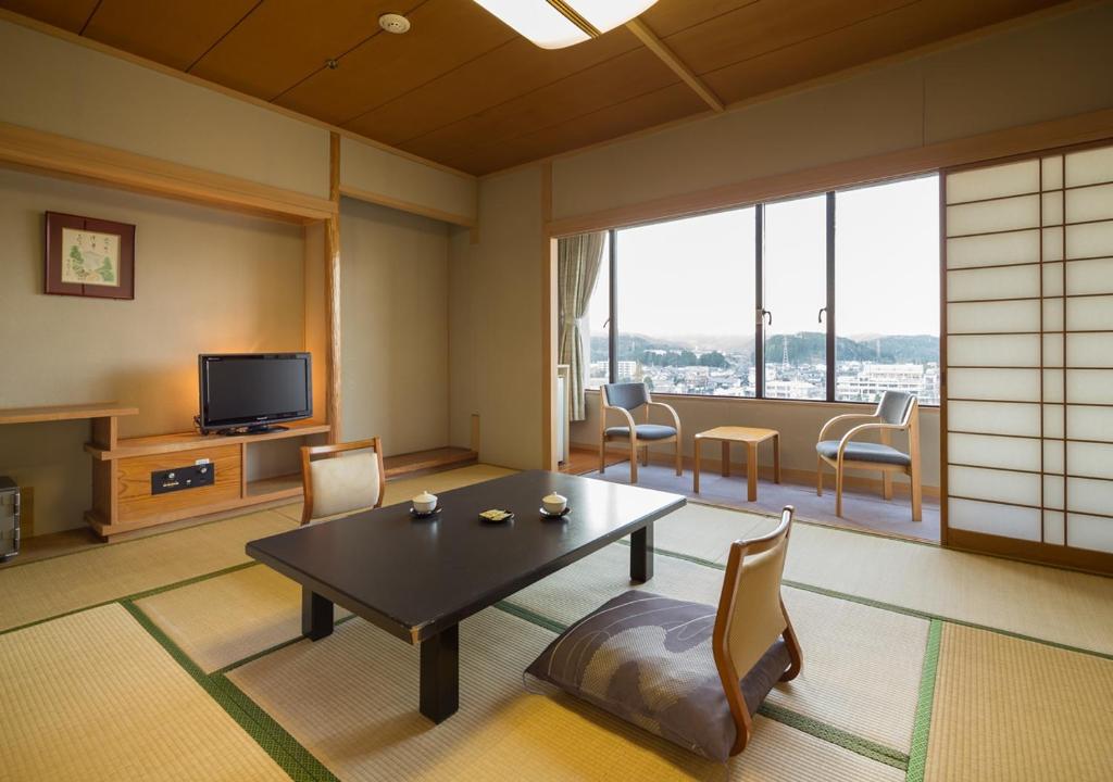 un salon avec une table, des chaises et une télévision dans l'établissement Wataya Besso, à Ureshino