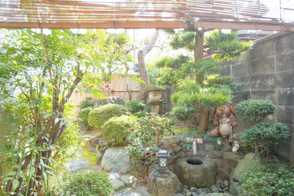 un jardin avec une statue, des arbres et des rochers dans l'établissement Kyo Obataya, à Kyoto