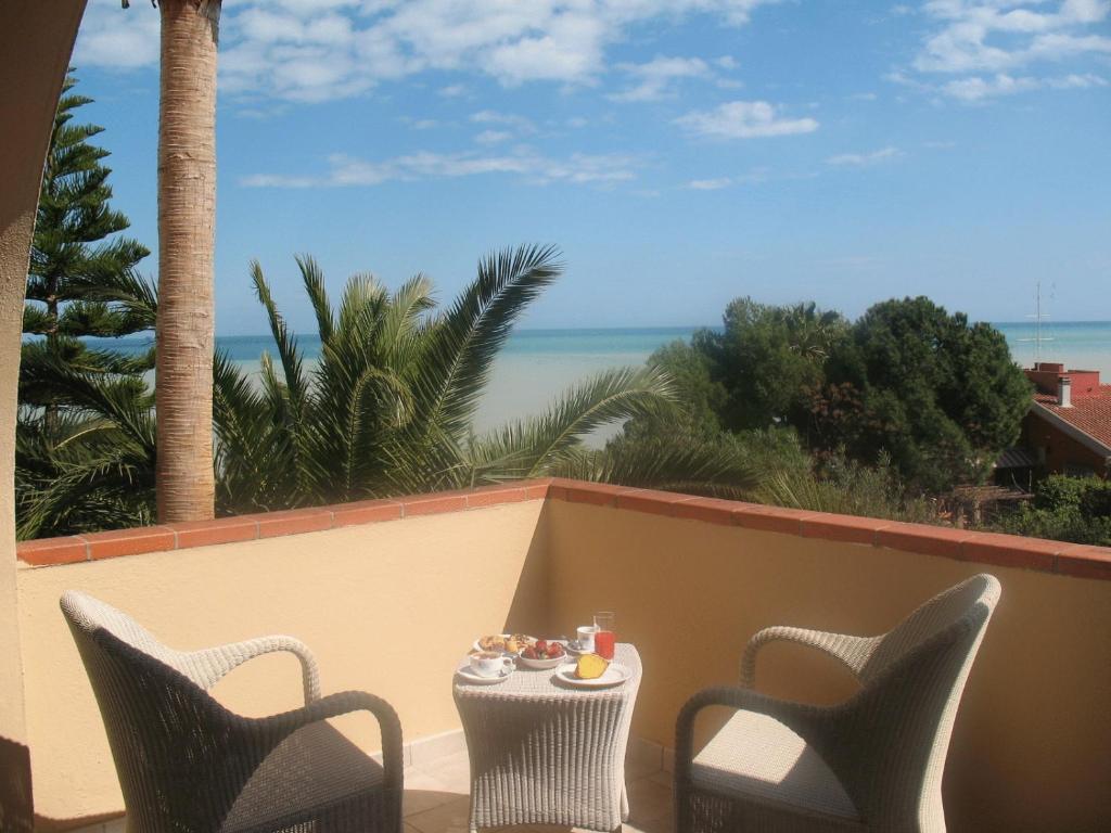 une table et des chaises sur un balcon avec vue sur l'océan dans l'établissement Helios Hotel, à Crotone