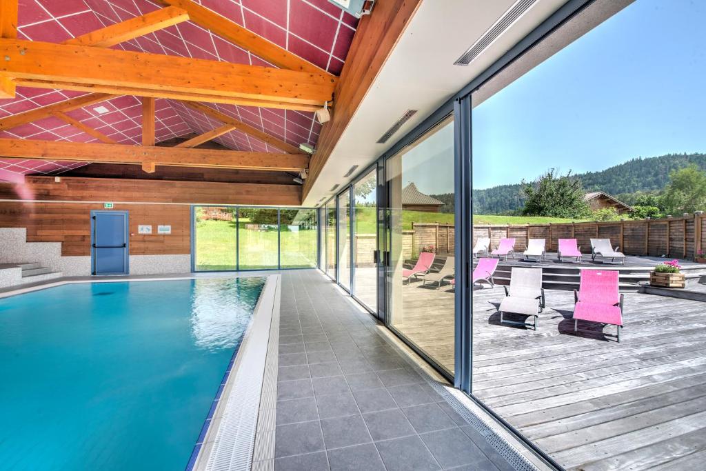 une maison avec une piscine et une terrasse dans l'établissement Village vacances Chalet de la Haute-Joux, à Cerniébaud