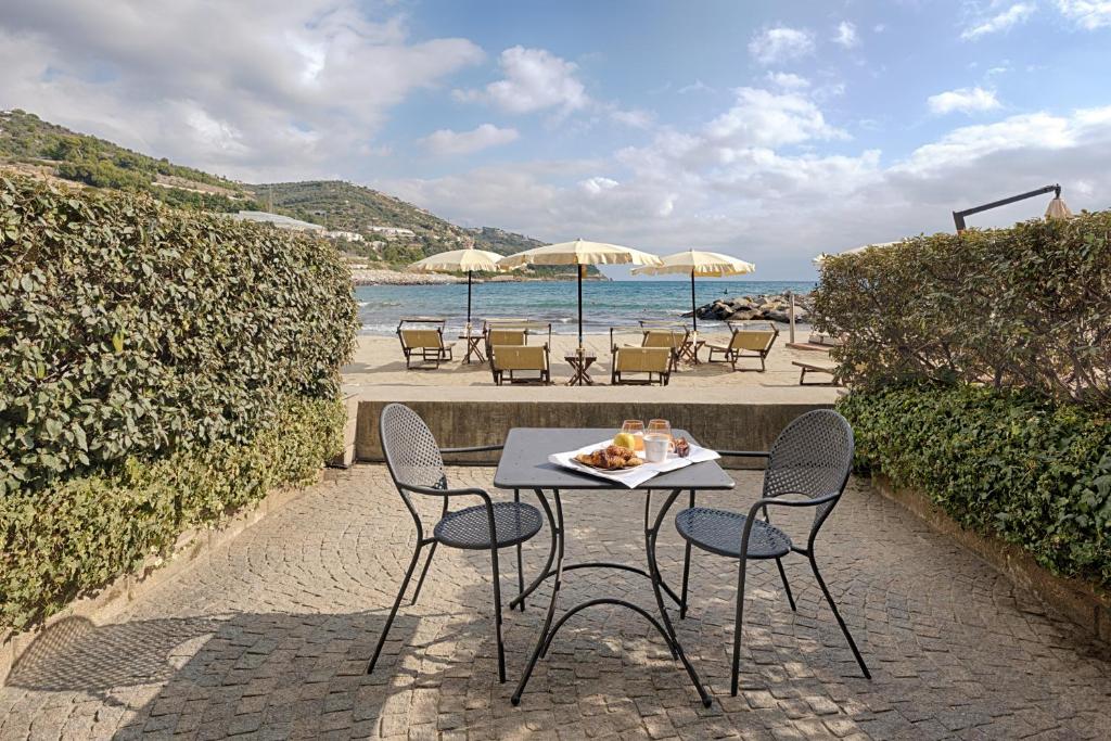 - une table et des chaises sur une terrasse à côté de la plage dans l'établissement Hotel Riviera dei Fiori, à San Lorenzo al Mare