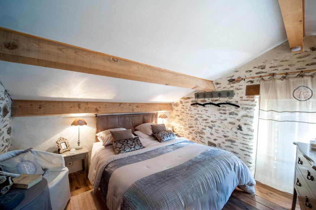 une chambre avec un lit et un mur en pierre dans l'établissement Gîte La Ribeyrette, à Chamborigaud