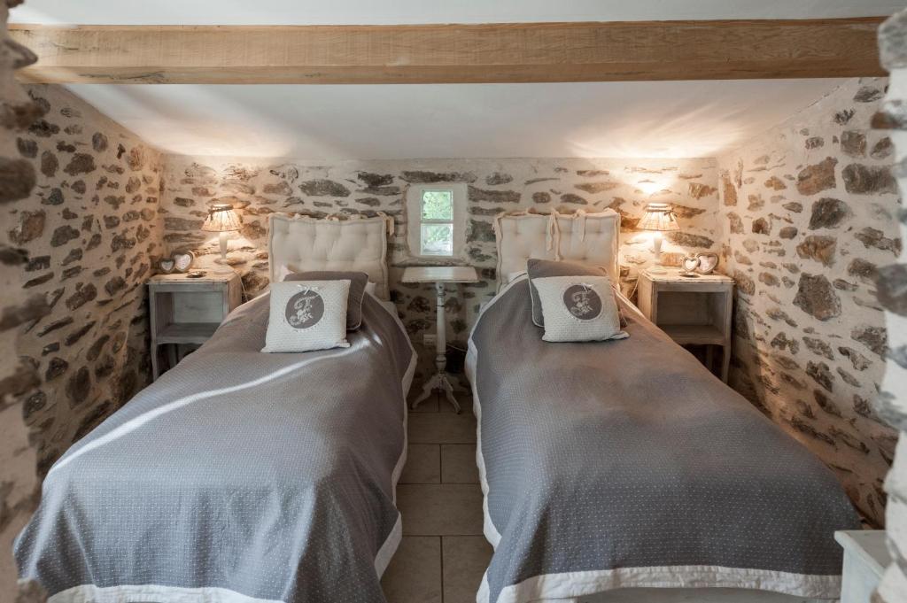 - 2 lits dans une chambre aux murs en pierre dans l'établissement Gîte La Ribeyrette, à Chamborigaud