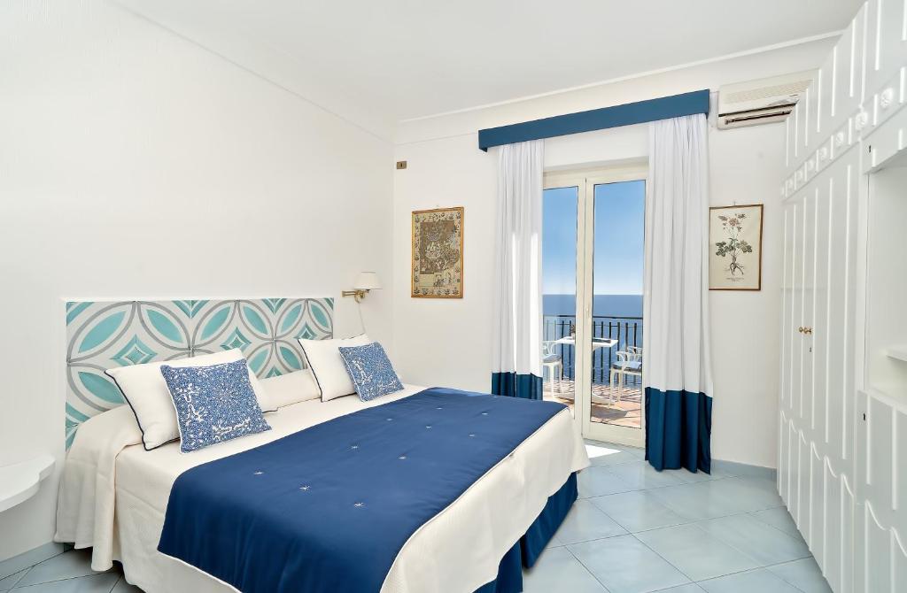 - une chambre avec un lit bleu et blanc et un balcon dans l'établissement Luxury Villas Positano, à Positano 183 autres photos