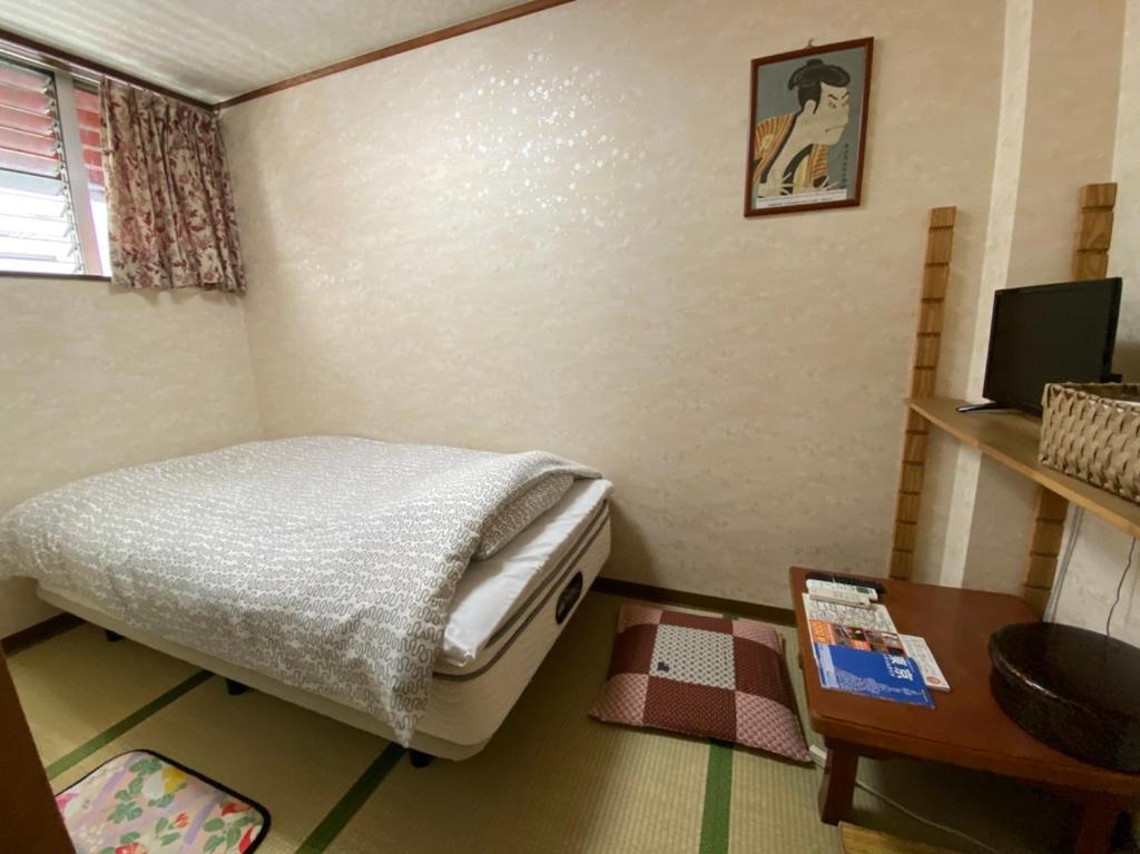 une petite chambre avec un lit et une table dans l'établissement Asakusa Ryokan Toukaisou, à Tokyo