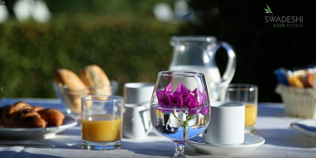une table avec deux verres et un pichet de jus d'orange dans l'établissement Swadeshi Sporting Hotel Tanca Manna, à Cannigione
