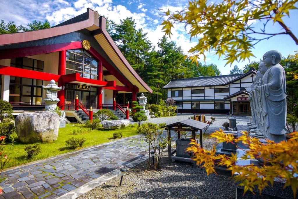 un grand bâtiment avec une statue devant lui dans l'établissement 金剛寺 宿坊 成穂院, à Matsukawa