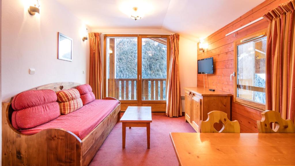 un salon avec un canapé et une télévision dans l'établissement Vacancéole - Résidence Les Chalets de la Ramoure, à Valfréjus