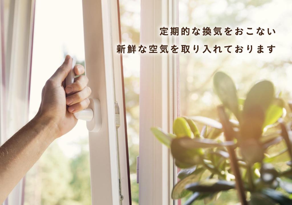 une main ouvrant une fenêtre avec une plante dans l'établissement Hotel AQUA Blue Yokosuka (Adult Only), à Yokosuka