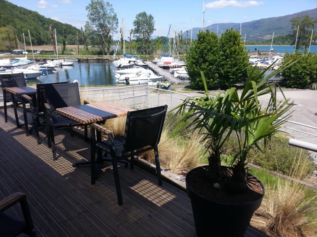 une terrasse avec des tables et des chaises ainsi qu'un port de plaisance dans l'établissement Eco Yourte Lac du Bourget, à Conjux