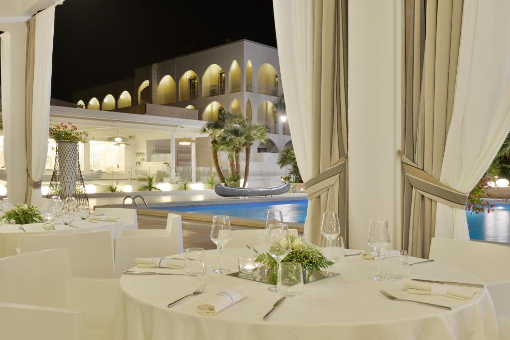 un restaurant avec des tables blanches, des chaises blanches et une piscine dans l'établissement Hotel Cerere, à Paestum 126 autres photos