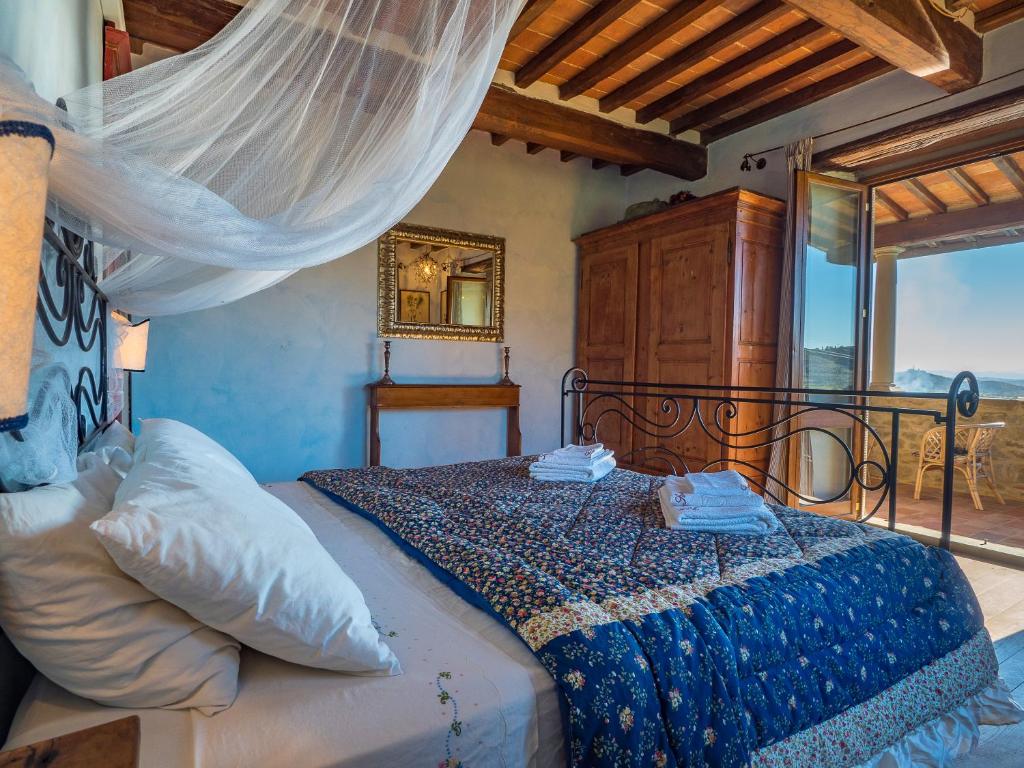 une chambre avec un lit avec une couette bleue et une fenêtre dans l'établissement Villa Senaia, à Castiglion Fiorentino 64 autres photos