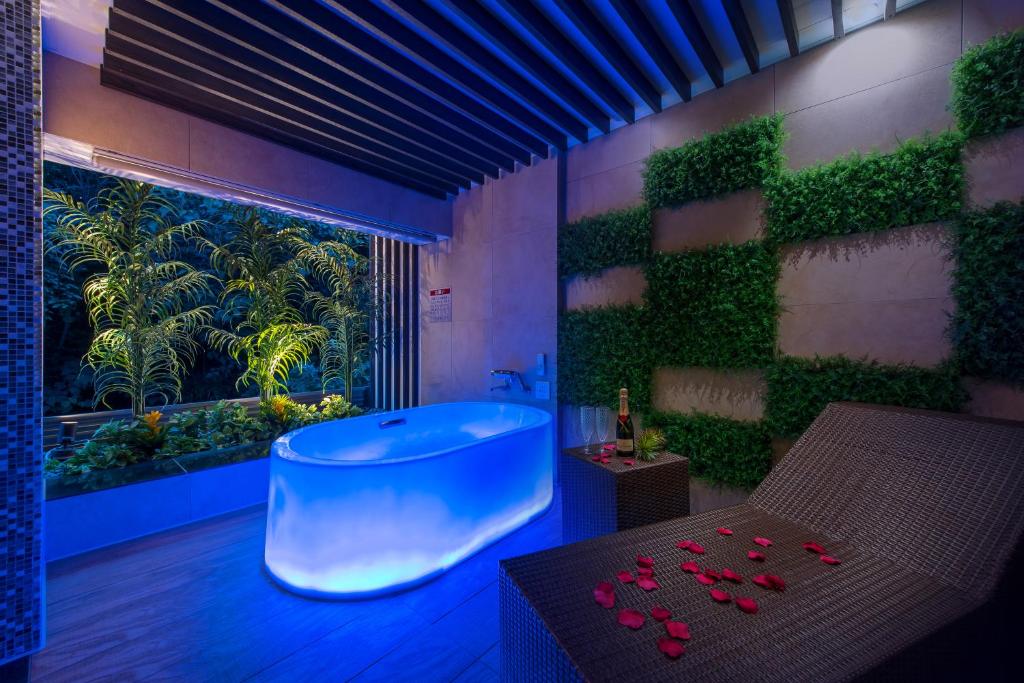 La salle de bains est pourvue d'une baignoire et d'une fenêtre ornée de plantes. dans l'établissement Hotel Lotus Iwatsuki (Adult Only), à Iwatsuki