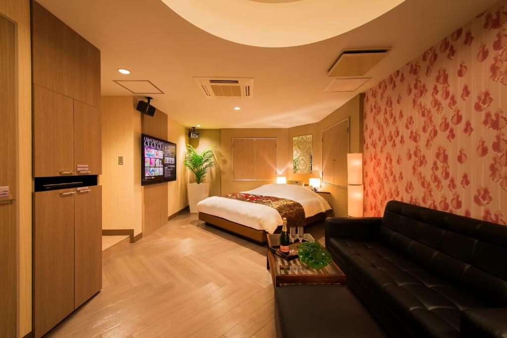 une chambre d'hôtel avec un lit et un canapé dans l'établissement Hotel CUE Machida(Adult Only), à Machida