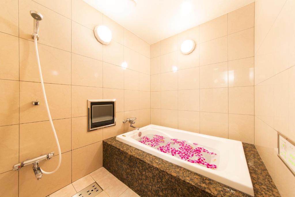 La salle de bains est pourvue d'une baignoire avec des fleurs roses. dans l'établissement Hotel Luna Sakuranomiya (Adult Only), à Osaka
