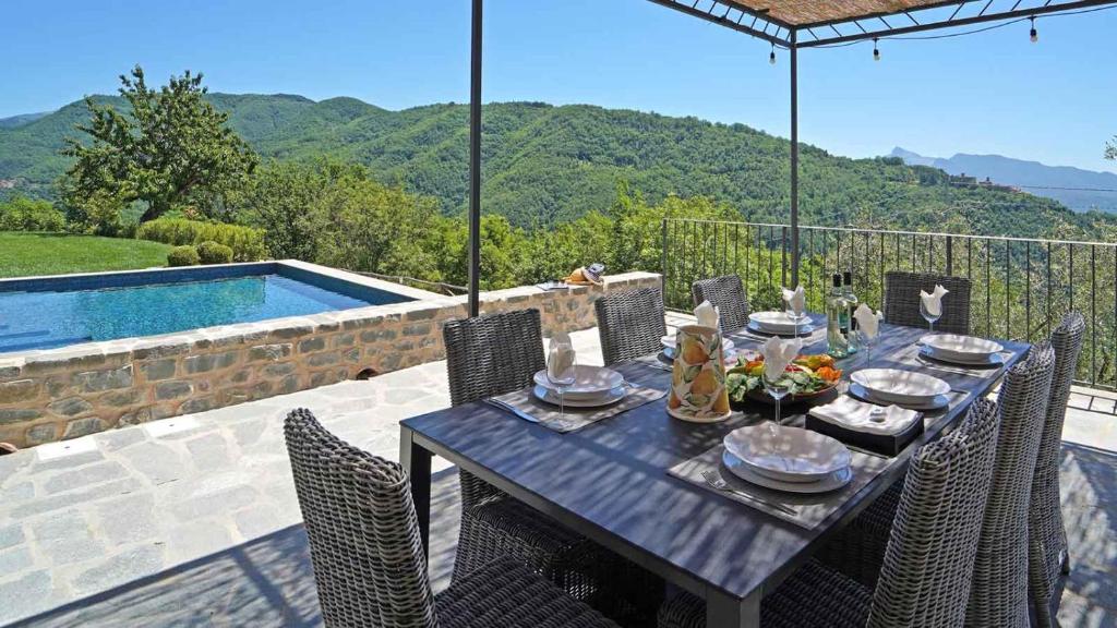 une table à manger et des chaises avec vue sur une piscine dans l'établissement Villa La Braja, à Licciana Nardi