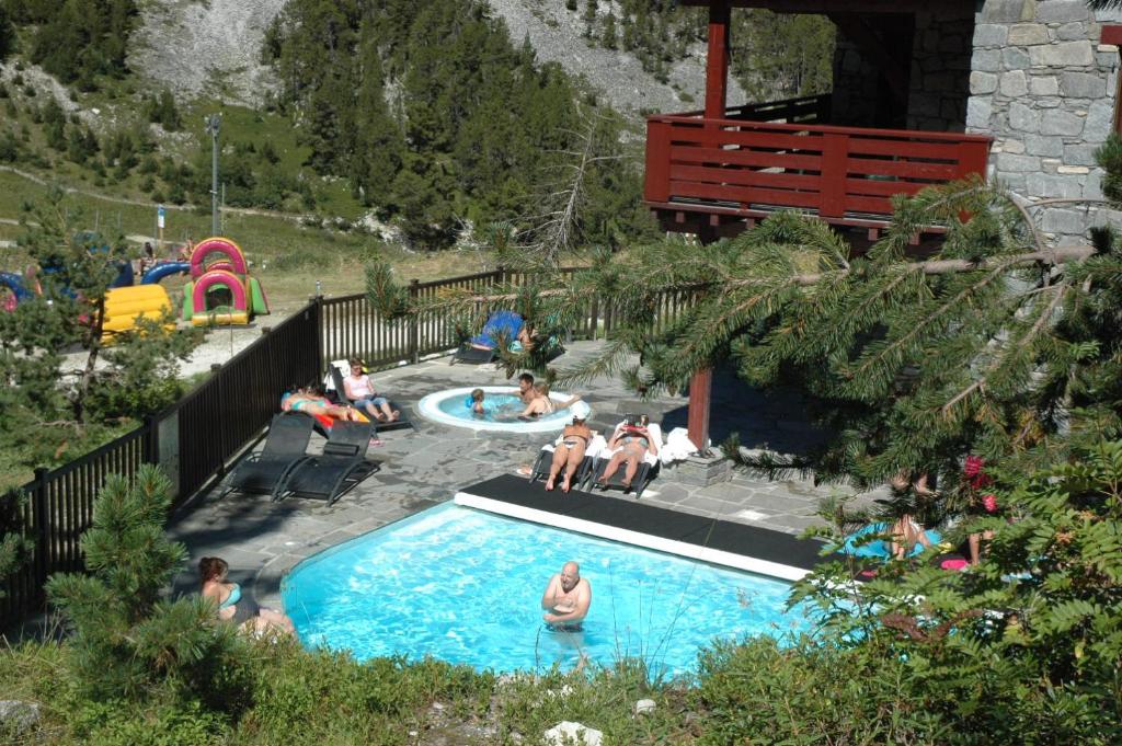 un groupe de personnes assises autour d'une piscine dans l'établissement Arc 1950 - Appartement 2 chambres - Ski-in & out - Grande Terrasse Ensoleillée, à Arc 1950
