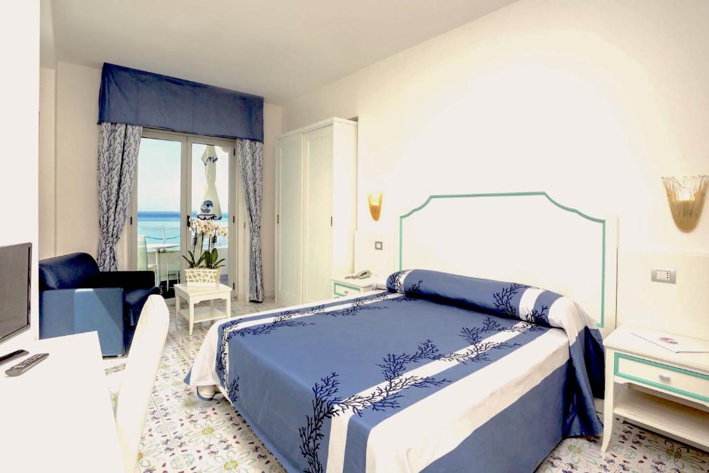 une chambre avec un lit bleu et blanc et une fenêtre dans l'établissement Hotel Ferretti, à Diamante