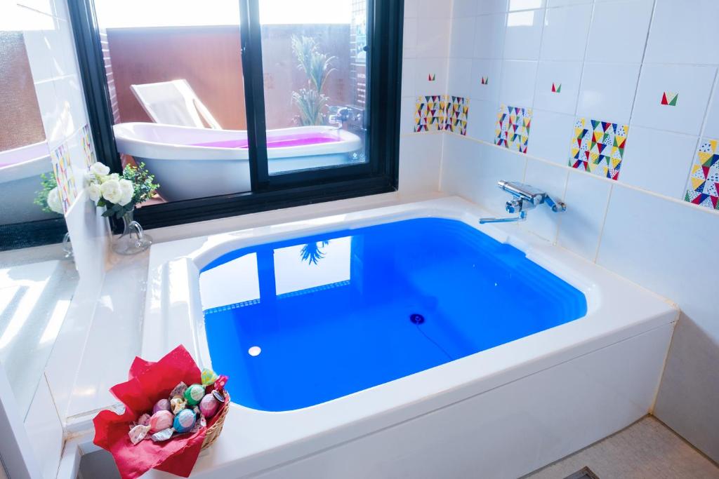 La salle de bains est pourvue d'une baignoire bleue et d'une fenêtre. dans l'établissement ホテルココナッツリゾートアミー Love Hotel, à Kagoshima 38 autres photos
