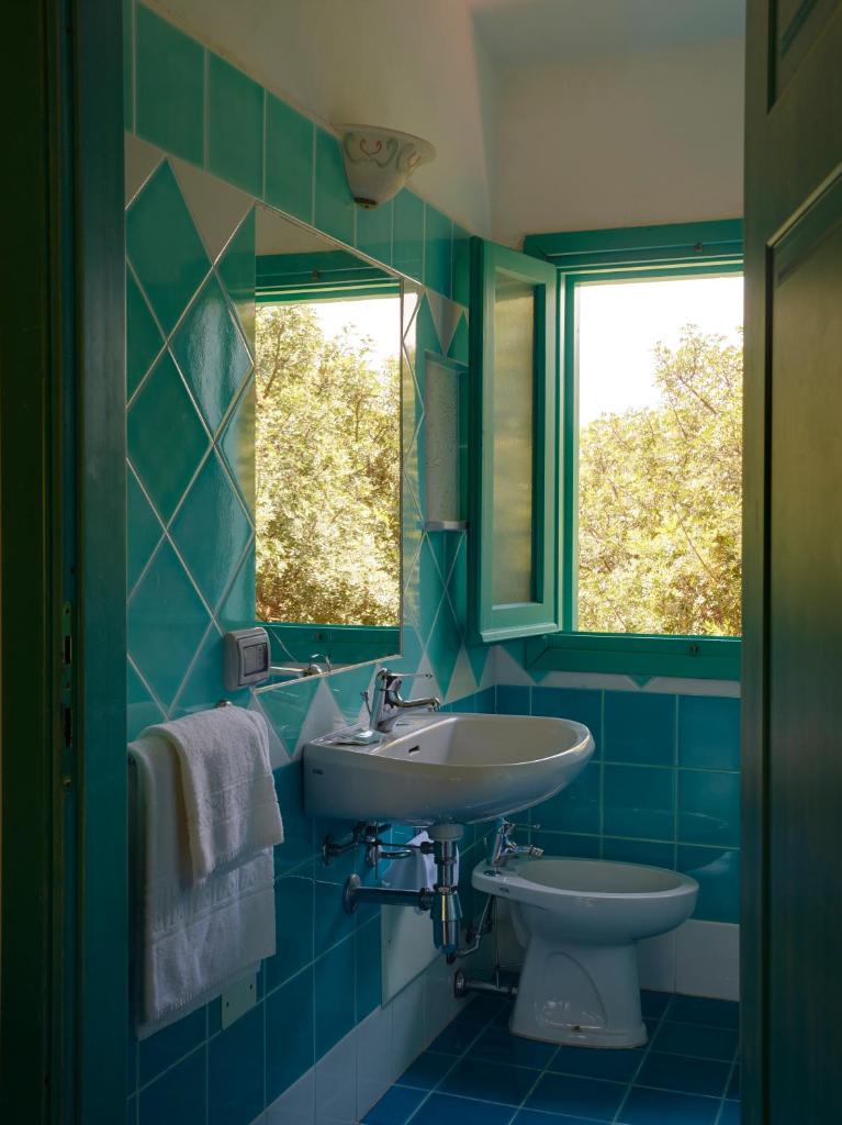 une salle de bain bleue avec un lavabo et des toilettes dans l'établissement Residence Hotel Lu Nibareddu, à San Teodoro