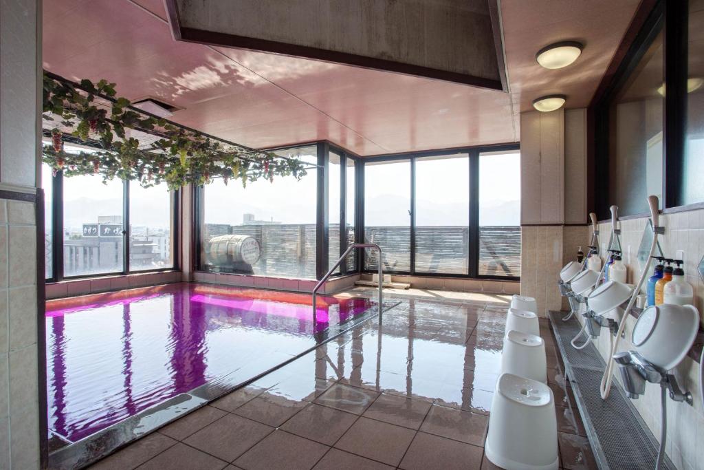 une grande salle de bains avec une piscine et des fenêtres dans l'établissement Hotel Hatta, à Fuefuki