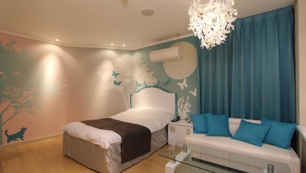 - une chambre avec un lit, un canapé et un lustre dans l'établissement Restay Sun City (Adult Only), à Utsunomiya
