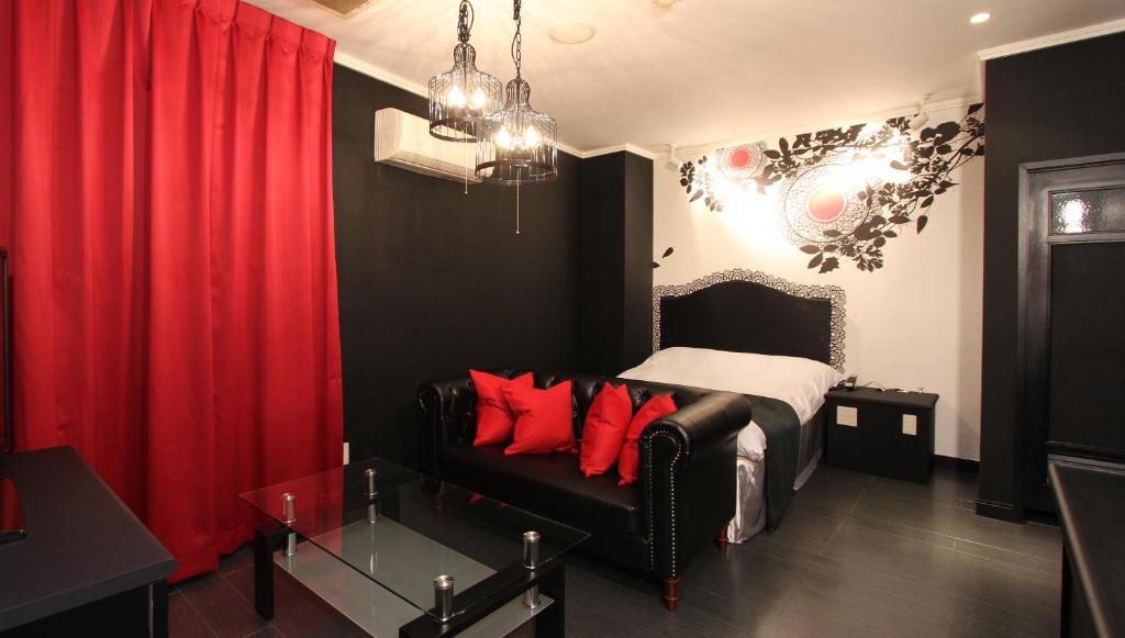 - une chambre avec un canapé et un lit avec des oreillers rouges dans l'établissement Restay Sun City (Adult Only), à Utsunomiya