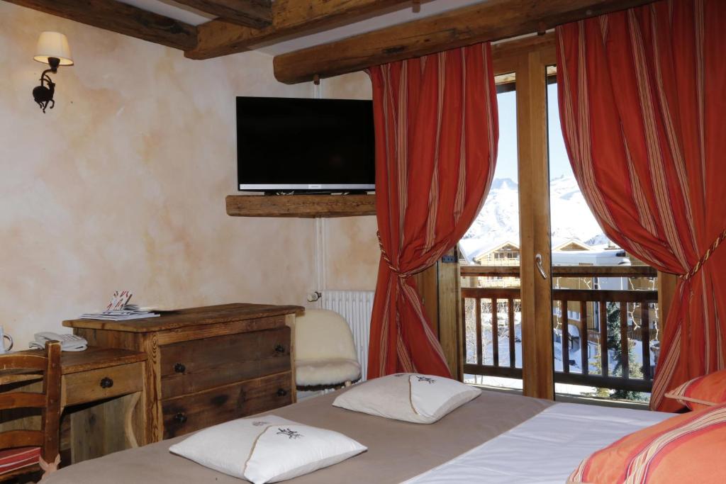 une chambre avec un lit et une télévision et un balcon dans l'établissement Alp'azur, à L'Alpe-d'Huez