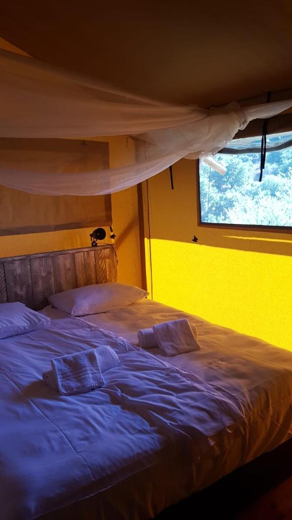 une chambre avec un lit bleu avec une fenêtre dans l'établissement Safaritent Glamping L'Ardechois, à Gluiras