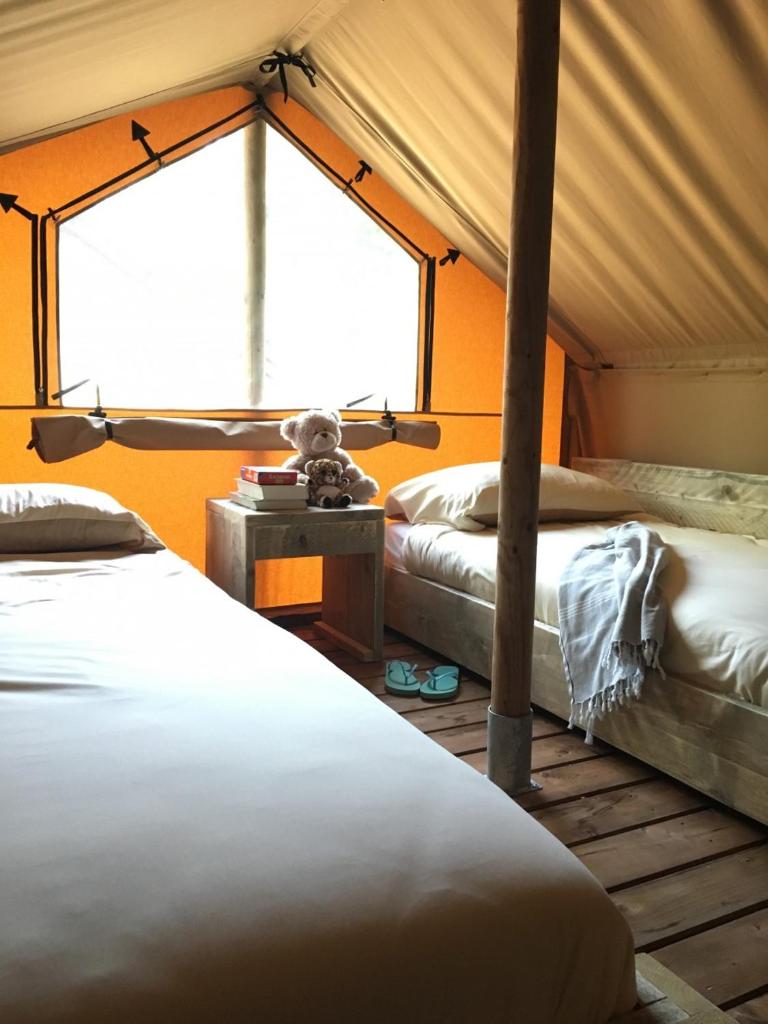 une chambre sous tente avec deux lits et une fenêtre dans l'établissement Safaritent Glamping L'Ardechois, à Gluiras