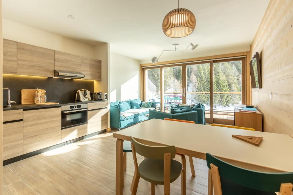 une cuisine et un salon avec une table et des chaises dans l'établissement LE RIDGE Appartement Premium - Les Arcs Paradiski, à Arc 1600