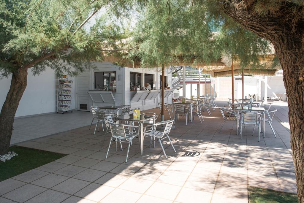 un patio avec des tables et des chaises sous un arbre dans l'établissement Grand Hotel Adriatico, à Montesilvano