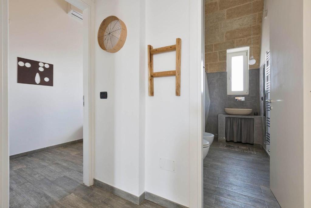 La salle de bains est pourvue de toilettes et d'une horloge murale. dans l'établissement Villa Toffi by Perle di Puglia, à Acquarica del Capo
