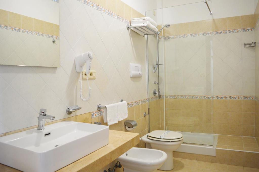 une salle de bain avec un lavabo, des toilettes et une douche dans l'établissement Paestum Inn Beach Resort, à Paestum