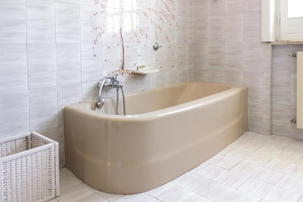 La salle de bains blanche est pourvue d'une baignoire et de confettis roses. dans l'établissement La Villa dei Limoni - Villa Panoramic with Pool, à Formia