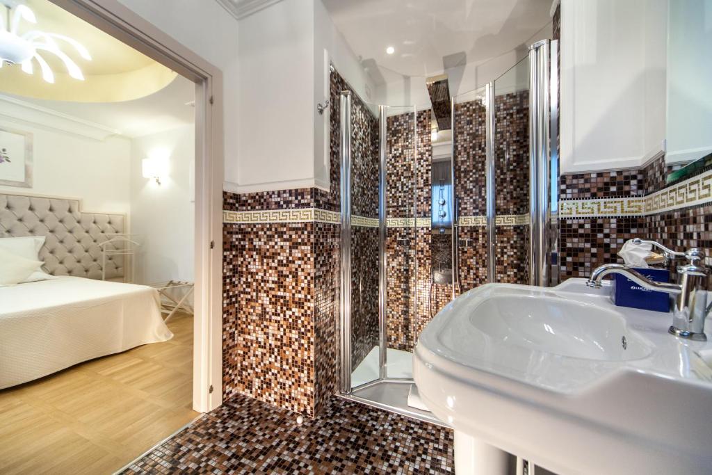 une salle de bain avec un lavabo et une douche et un lit dans l'établissement Hotel Aurelia, à Milano Marittima
