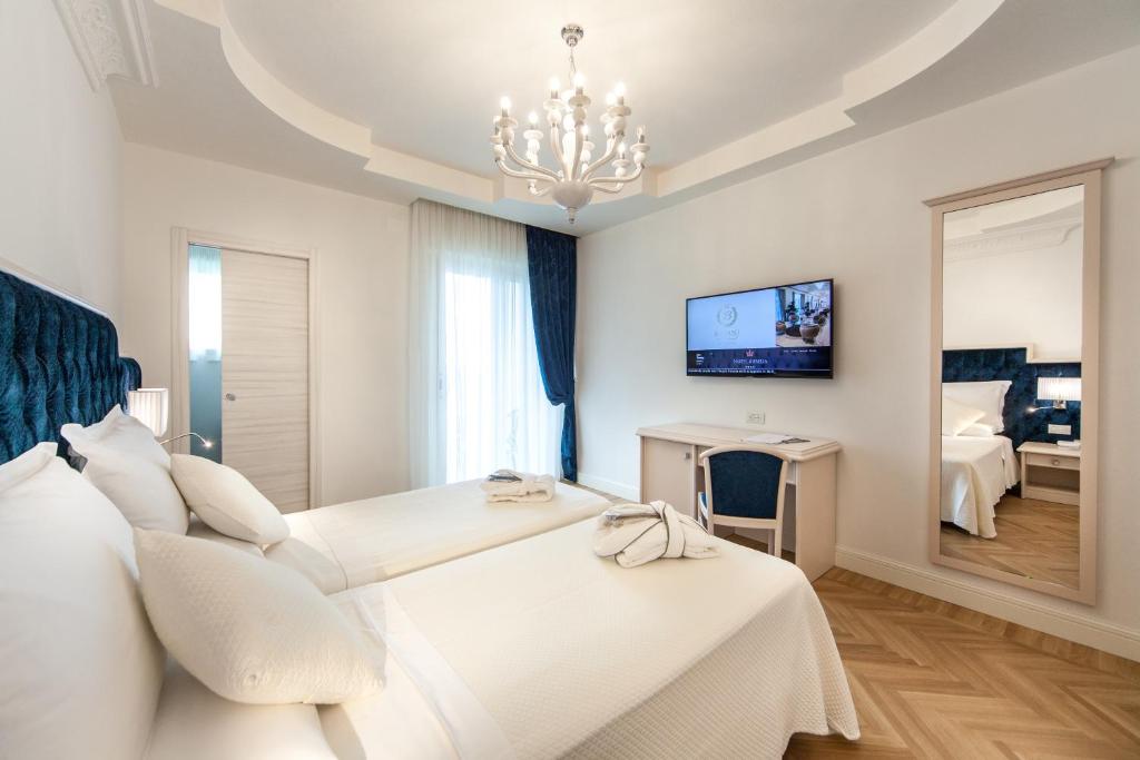 une chambre blanche avec un lit et un miroir dans l'établissement Hotel Aurelia, à Milano Marittima