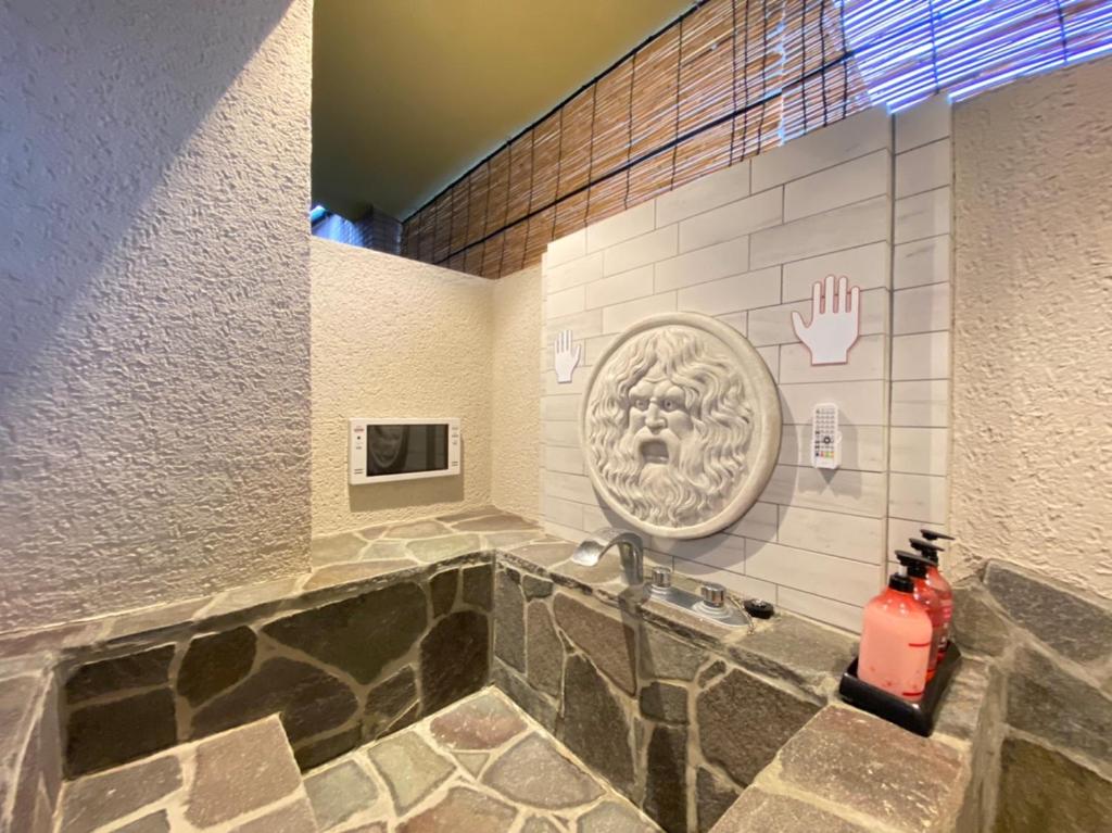 une salle de bain avec une baignoire en pierre avec un lavabo dans l'établissement Hana No Shizuku, à Ureshino