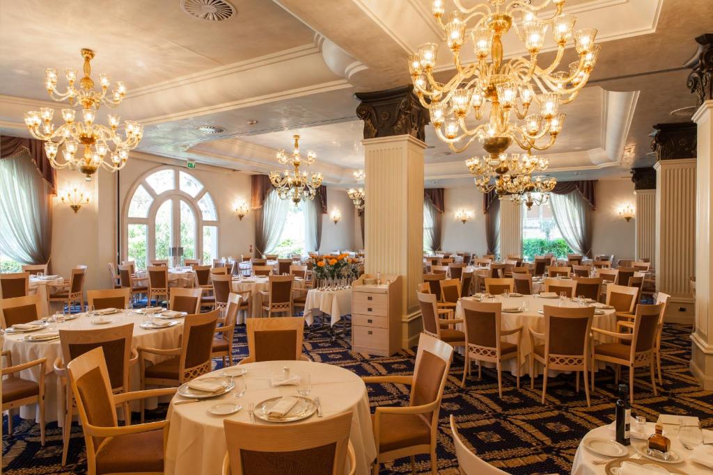 une salle de banquet avec des tables blanches, des chaises et des lustres dans l'établissement Palace Hotel, à Milano Marittima 61 autres photos