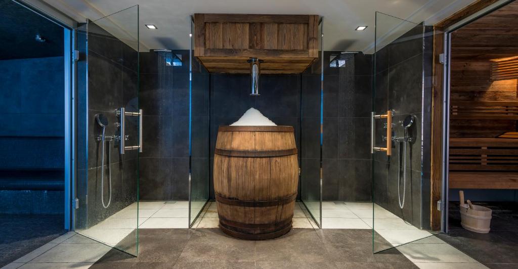 une salle de bain avec un tonneau en bois et des murs en verre dans l'établissement Le Kaïla, à Méribel