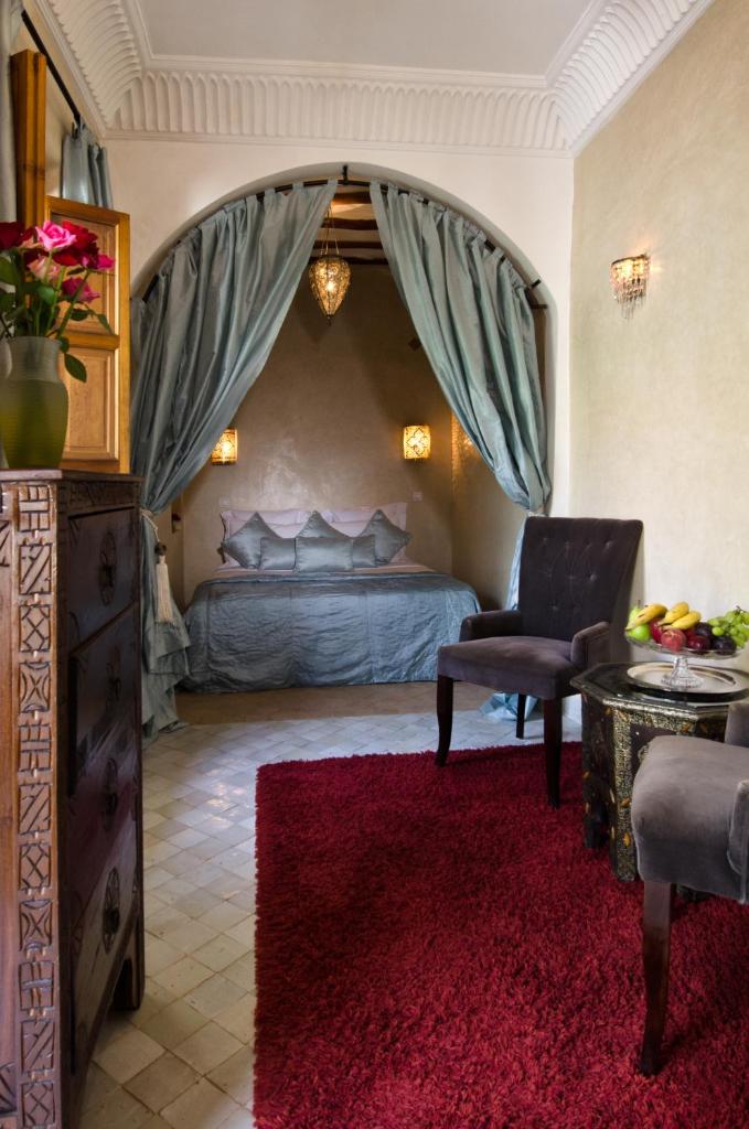 - une chambre avec un lit, une chaise et un tapis rouge dans l'établissement Dar Rocmarra, à Marrakech
